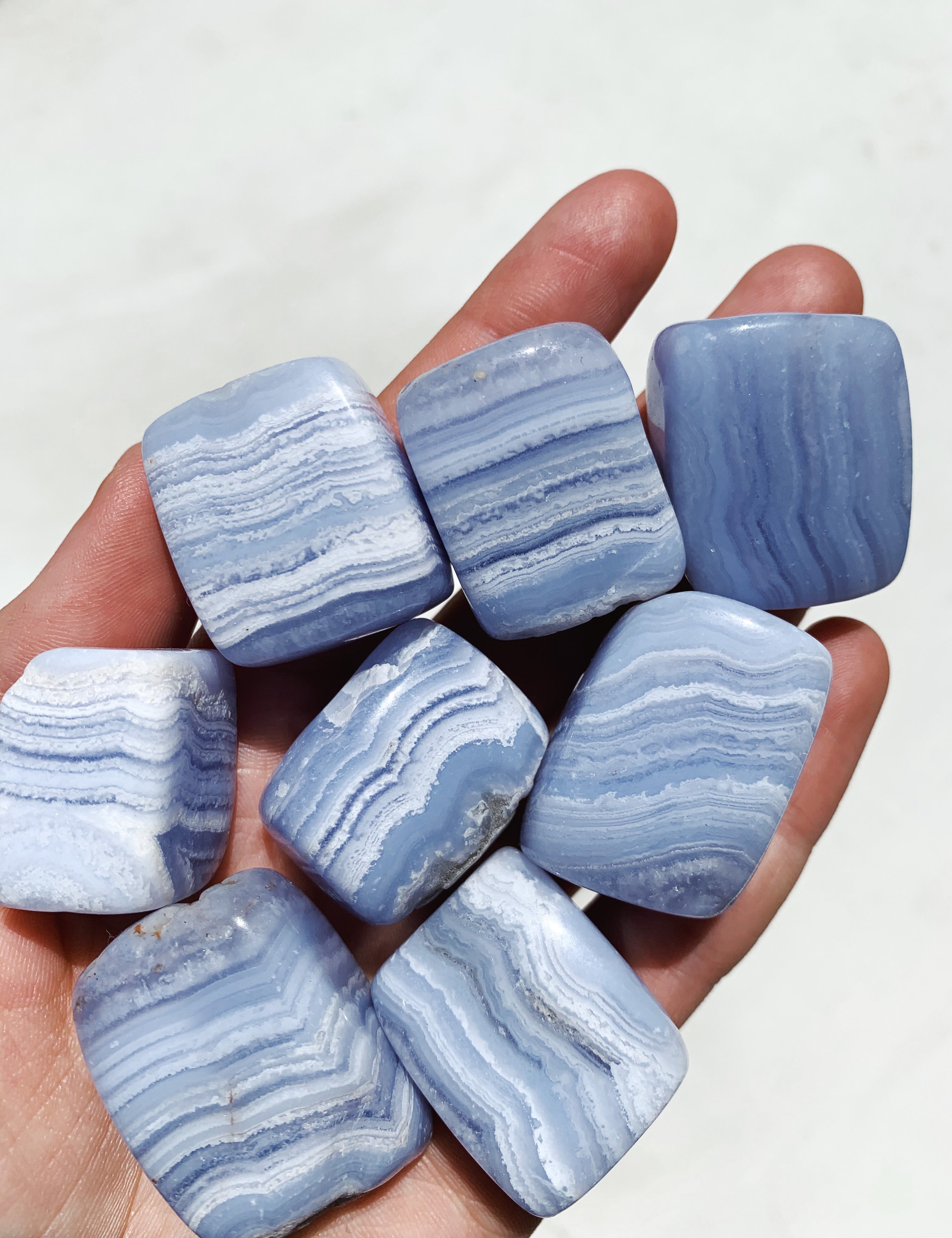 a hand holding Blue Lace Agate Tumbled crystals
