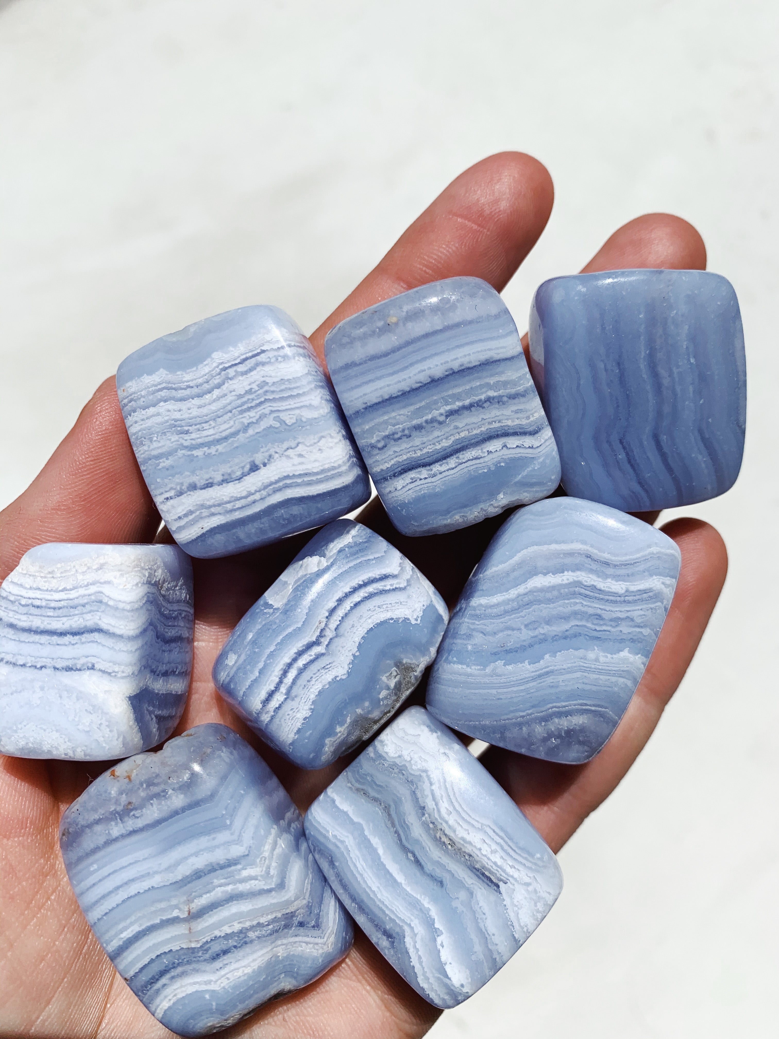 a hand holding Blue Lace Agate Tumbled crystals
